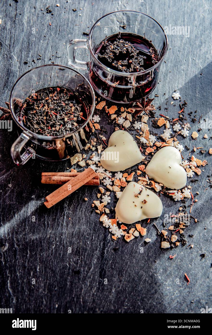 vin chaud dans deux verres avec des biscuits en forme de coeur et des épices disposés sur un fond gris ardoise Banque D'Images