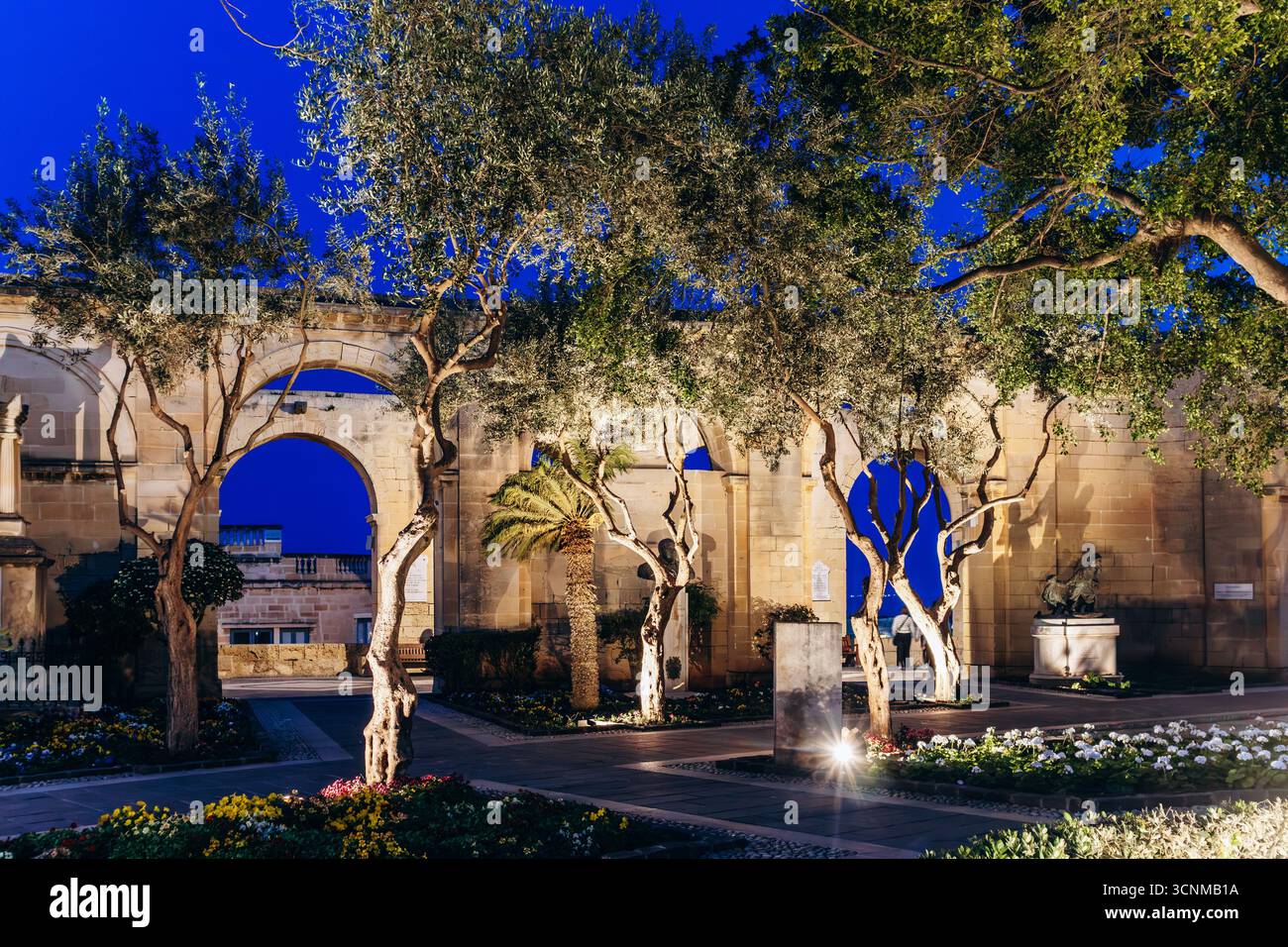 Vue nocturne sur les arches illuminées, les arbres et les fleurs dans les jardins supérieurs de Barrakka, un parc public historique offrant une vue panoramique sur le Grand Banque D'Images
