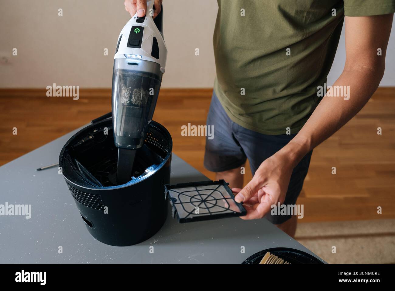 Gros plan rogné de l'humidificateur d'air de nettoyage masculin avec aspirateur à main, enlevant soigneusement la poussière du filtre et des composants internes pour améliorer Banque D'Images