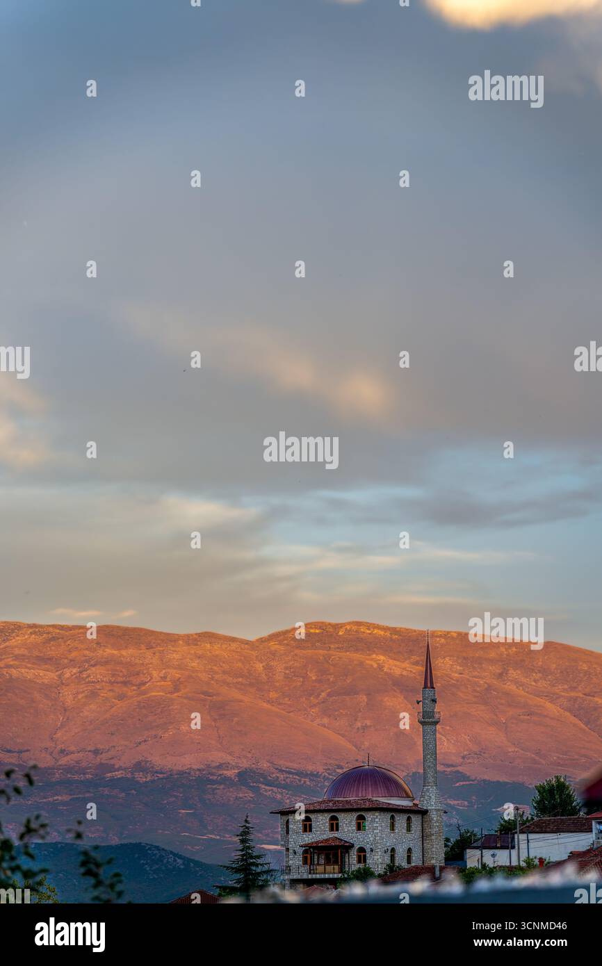 Coucher de soleil paisible sur la mosquée de Pogradec, Albanie - Une vue sereine de la foi, de l'architecture et des montagnes majestueuses dans la lumière dorée de la soirée Banque D'Images