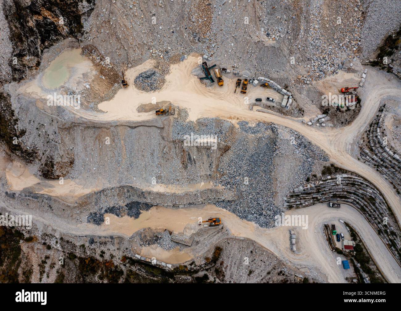 Vue aérienne du paysage accidenté et en terrasses sculpté par les carrières de marbre, machines reposant au milieu de la pierre dure, grise et blanche, Carrare, Toscane, Italie. Banque D'Images