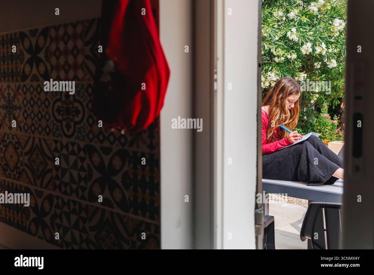 Vue sur la fenêtre de la cuisine de l'adolescente journal dans le jardin Banque D'Images