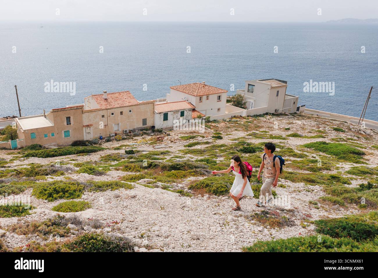 Un homme et une fille grimpent sur une colline calcaire au-dessus de la Méditerranée Banque D'Images