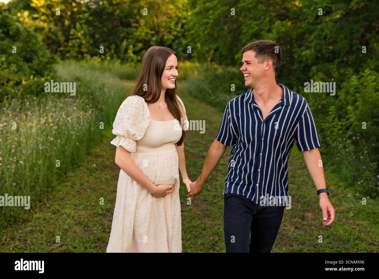 heureux attendant couple tenant la main dans un champ Banque D'Images