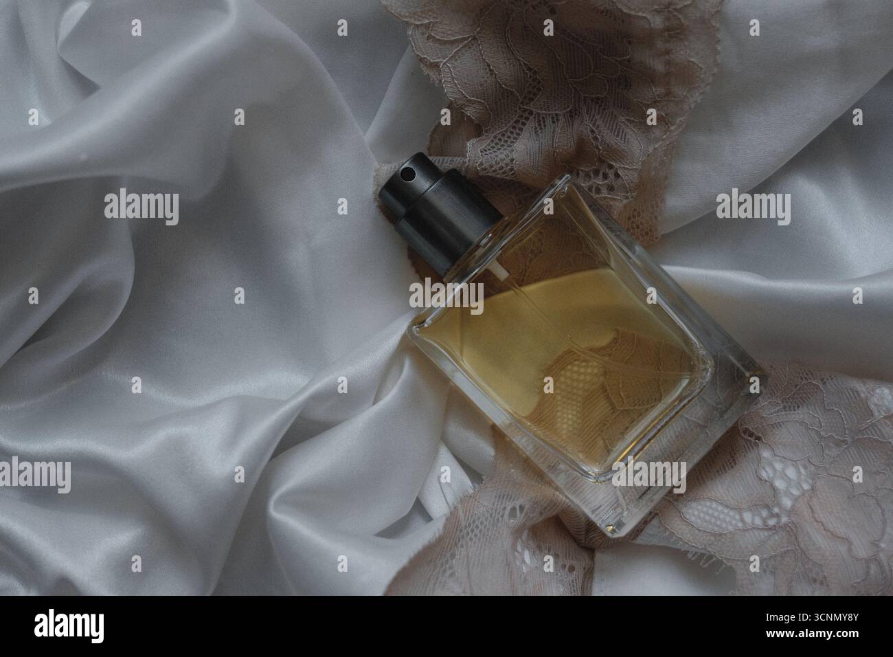bouteille de parfum sur fond de soie blanche Banque D'Images