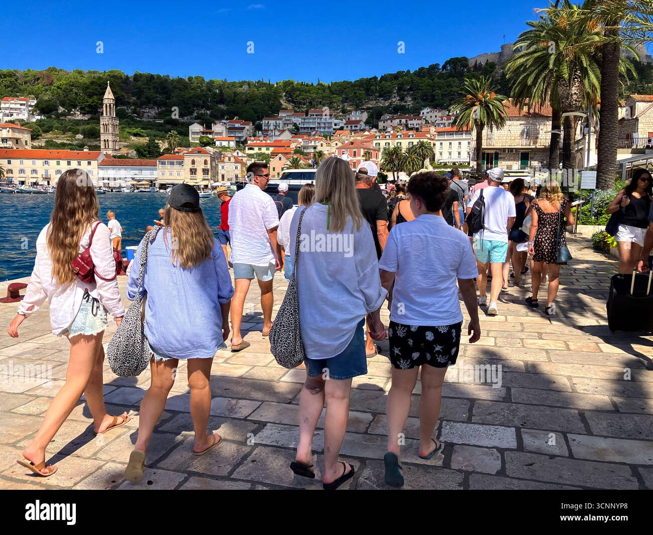 Les jeunes touristes marchent le long de la promenade dans la ville balnéaire populaire de Hvar sur l'île croate de Hvar pendant l'été 2025 Banque D'Images