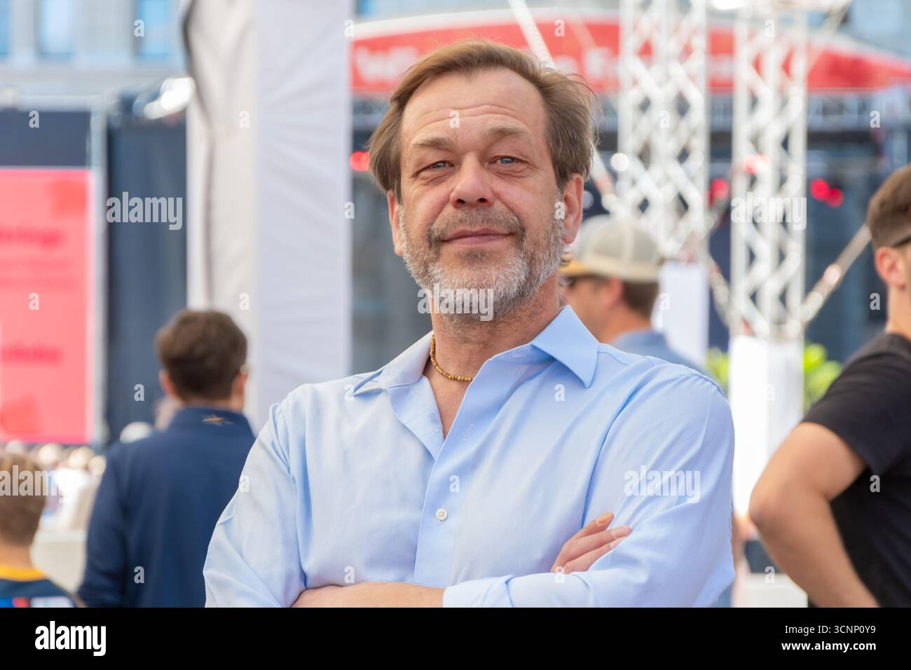 Portrait d'un homme confiant âgé de 50-55 ans dans une chemise bleue contre une foule de gens Banque D'Images
