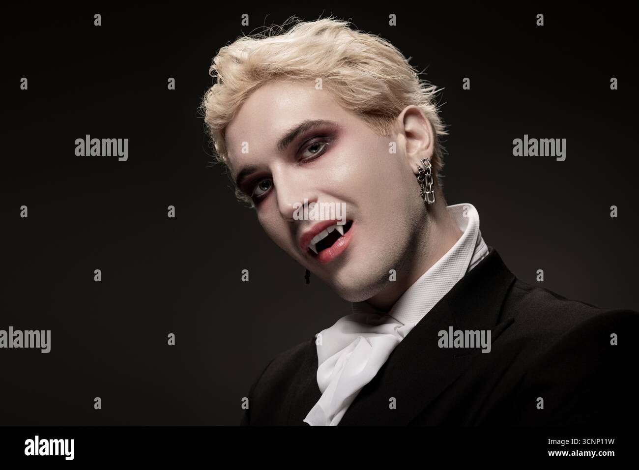 Un beau jeune homme pose avec confiance dans un grand costume d'Halloween pour un événement nocturne. Banque D'Images