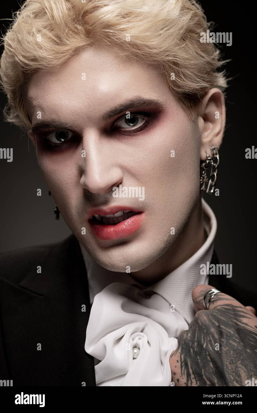 Un beau jeune homme porte fièrement un costume d'Halloween épique et détaillé et un maquillage audacieux. Banque D'Images