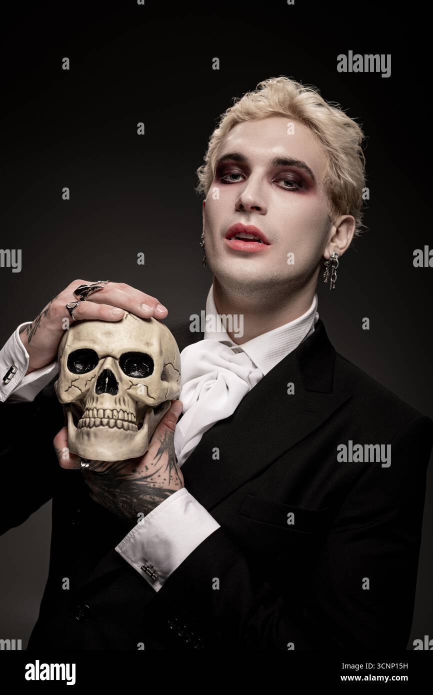 Un jeune homme présente son costume créatif d'Halloween tout en tenant un crâne. Banque D'Images