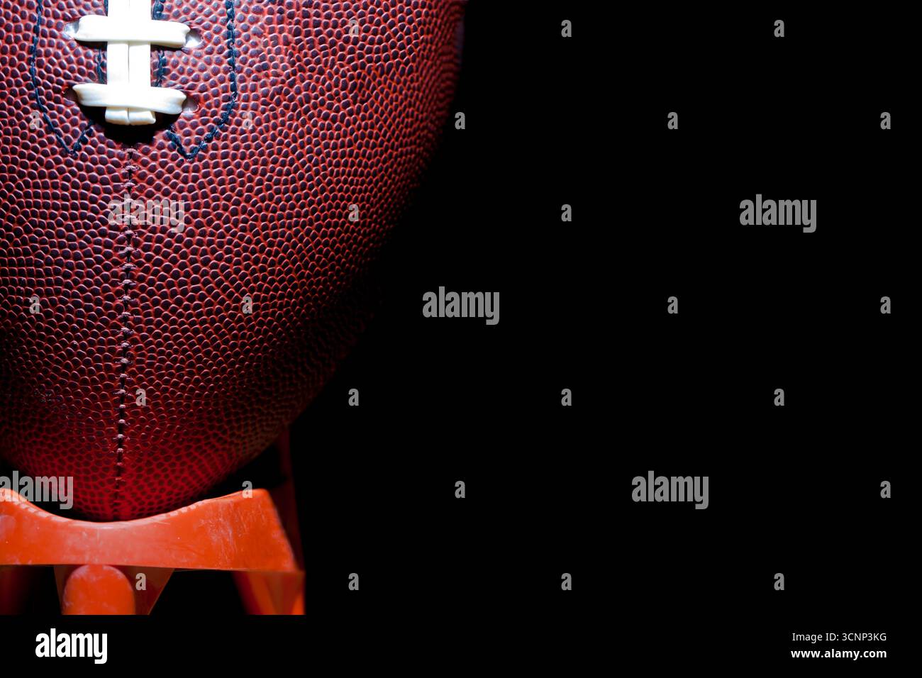Un gros plan d'un football américain révèle une texture de cuir détaillée et des coutures précises, photographiées en studio sur fond noir, highli Banque D'Images