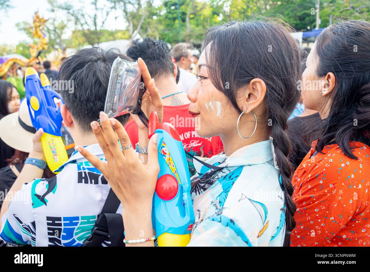 2025 Festival Songkran, Bangkok, Thaïlande. Femme festivalière prenant une photo avec un smartphone dans un étui étanche ; poudre de talc sur le visage Banque D'Images