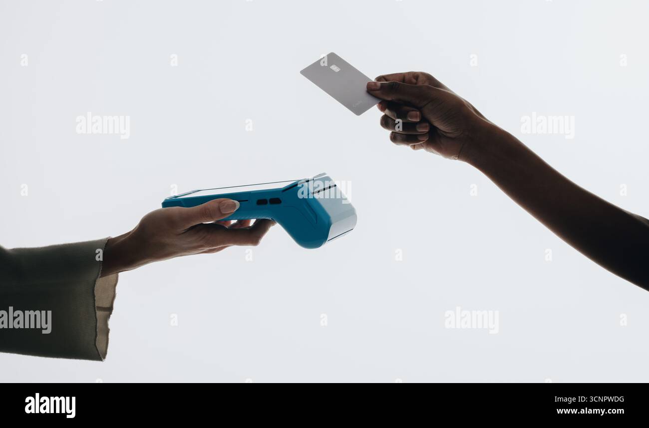 Gros plan d'une action de paiement sans contact, mettant en vedette une main tenant un lecteur de carte et une autre main présentant une carte de crédit, symbolisant le cachet moderne Banque D'Images