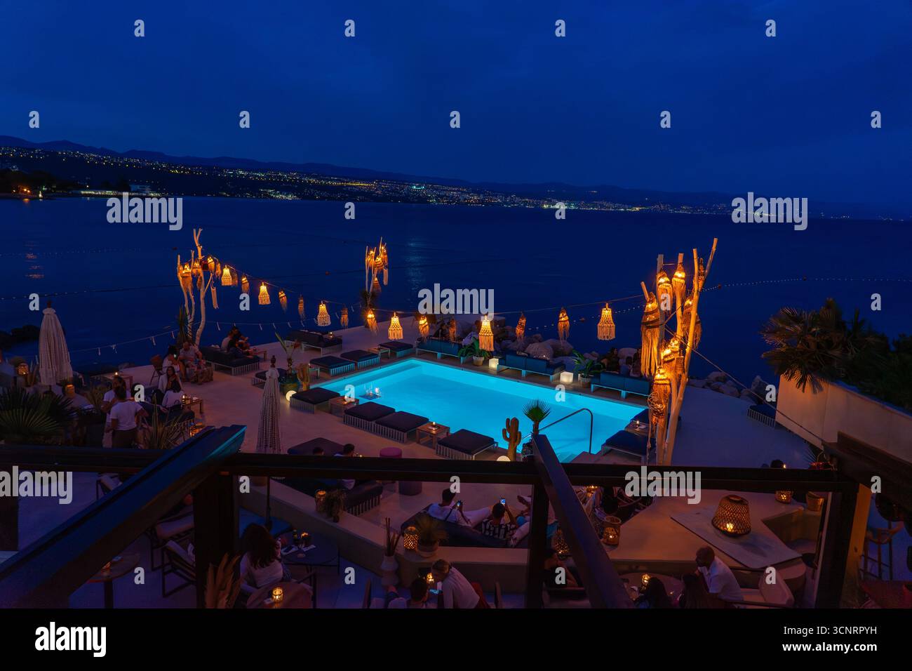 Salon chic sur le toit en bord de mer avec piscine incandescente, lanternes et vue sur l'océan à Opatia Croatie. Banque D'Images
