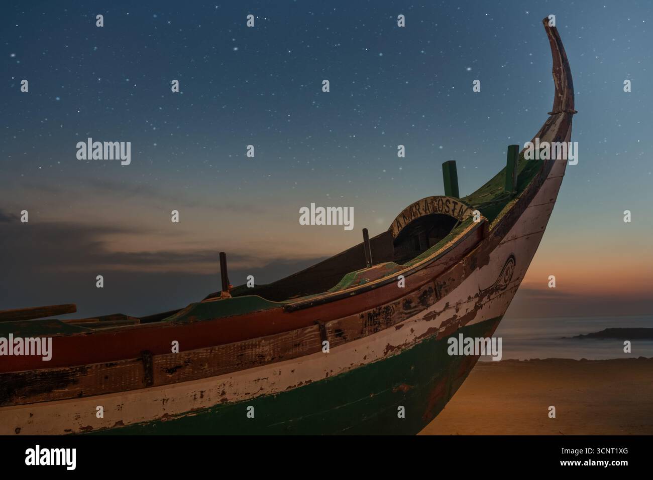 Vieux bateau de pêche en bois sur la plage de sable sous le ciel étoilé de nuit avec l'horizon crépusculaire et l'atmosphère calme de l'océan Banque D'Images
