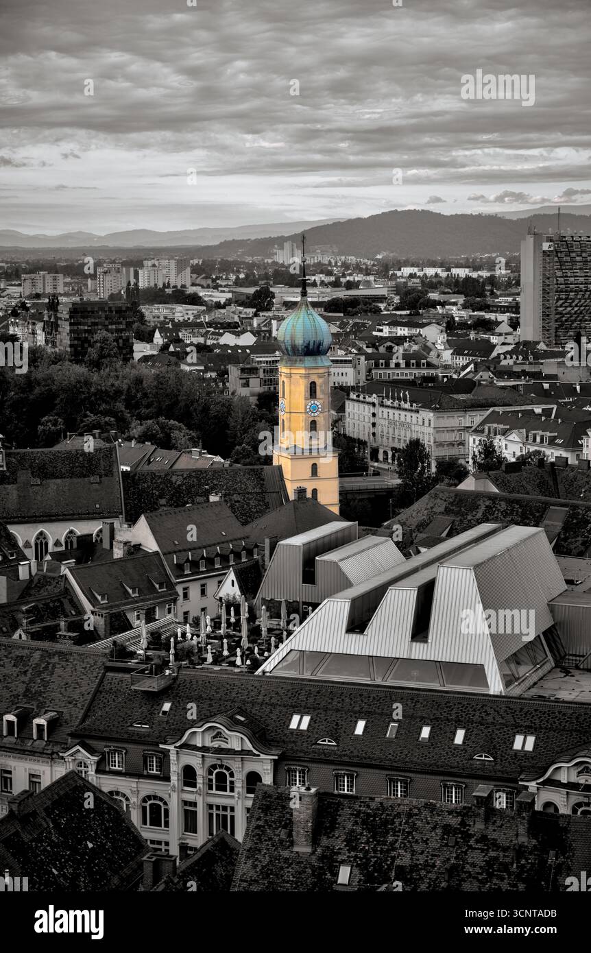 Une vue spectaculaire en hauteur de Graz mettant en évidence la tour aux couleurs vives de la Mariahilferkirche sur un fond de ville désaturé Banque D'Images