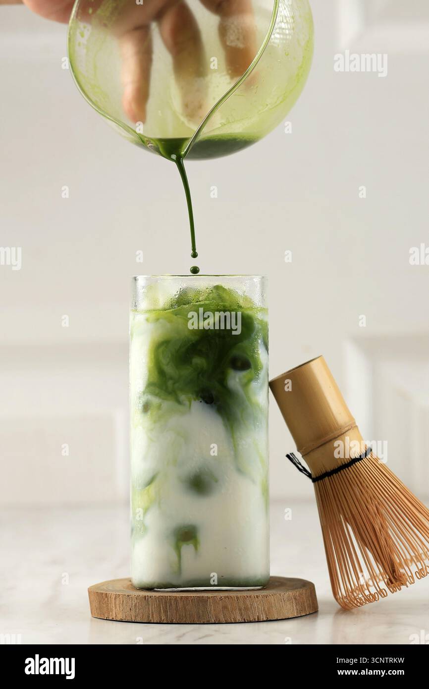 Versez le thé vert Matcha sur le lait sur la table blanche, Latte Matcha Greentea glacé Banque D'Images