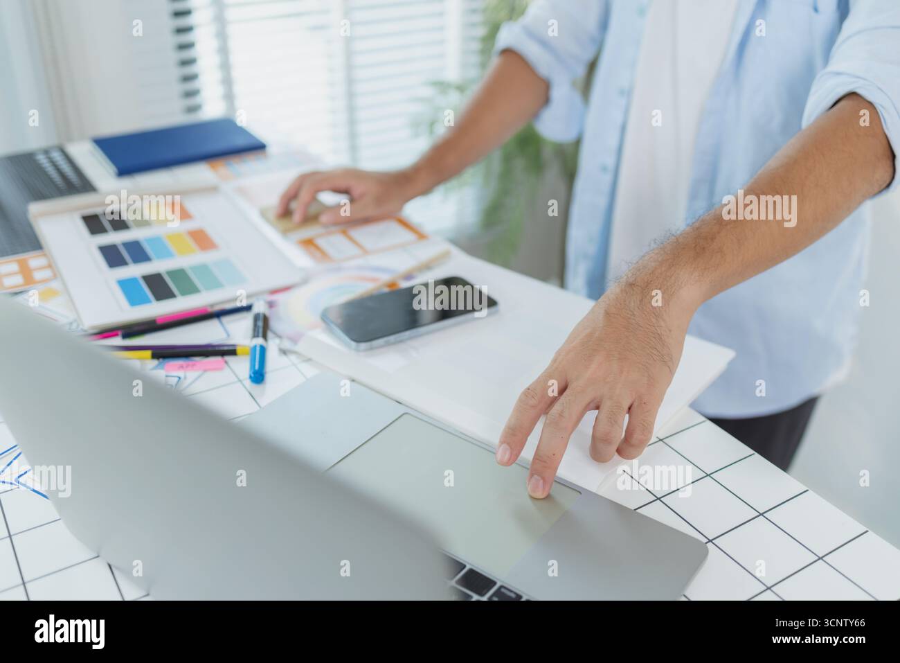 Un concepteur créatif travaille sur la planification UX/UI, analysant des croquis et des prototypes sur un tableau blanc tout en utilisant un ordinateur portable. Le processus montre la pensée de conception Banque D'Images