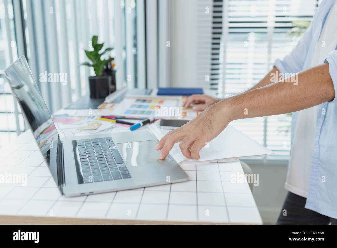 Un concepteur créatif travaille sur la planification UX/UI, analysant des croquis et des prototypes sur un tableau blanc tout en utilisant un ordinateur portable. Le processus montre la pensée de conception Banque D'Images
