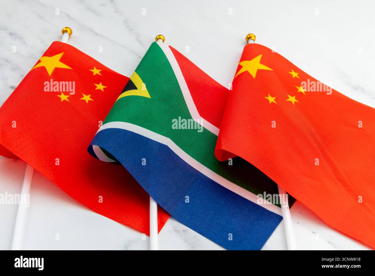 Le drapeau national de l'Afrique du Sud sur le mât de drapeau entre le drapeau national chinois. Un concept de relations entre l'Afrique du Sud et la Chine. Banque D'Images