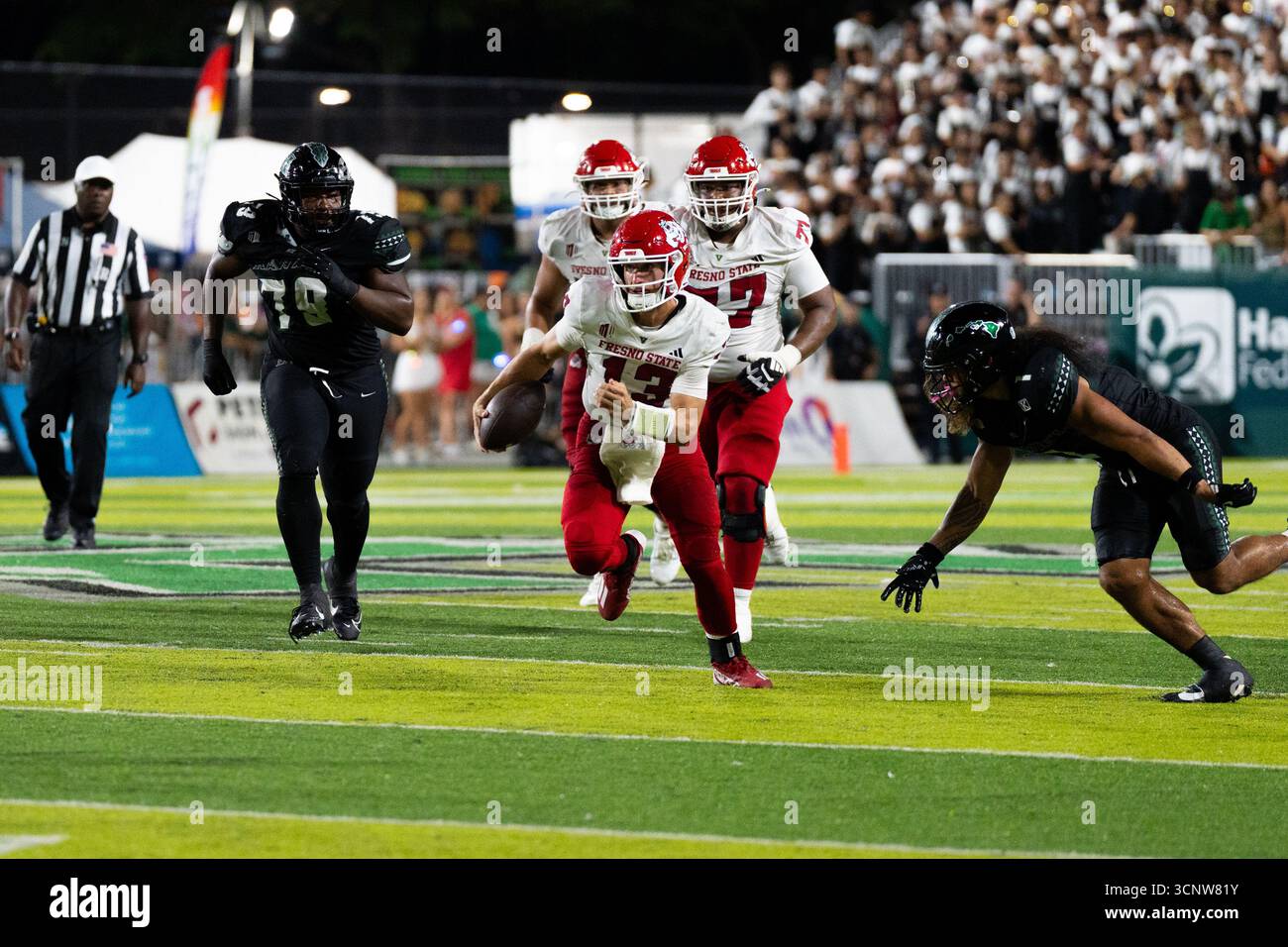 Fresno State QB E.J. Warner se bat contre les défenseurs d'Hawaï dans une victoire étroite de 23 à 21, montrant l'agilité sous pression. Banque D'Images