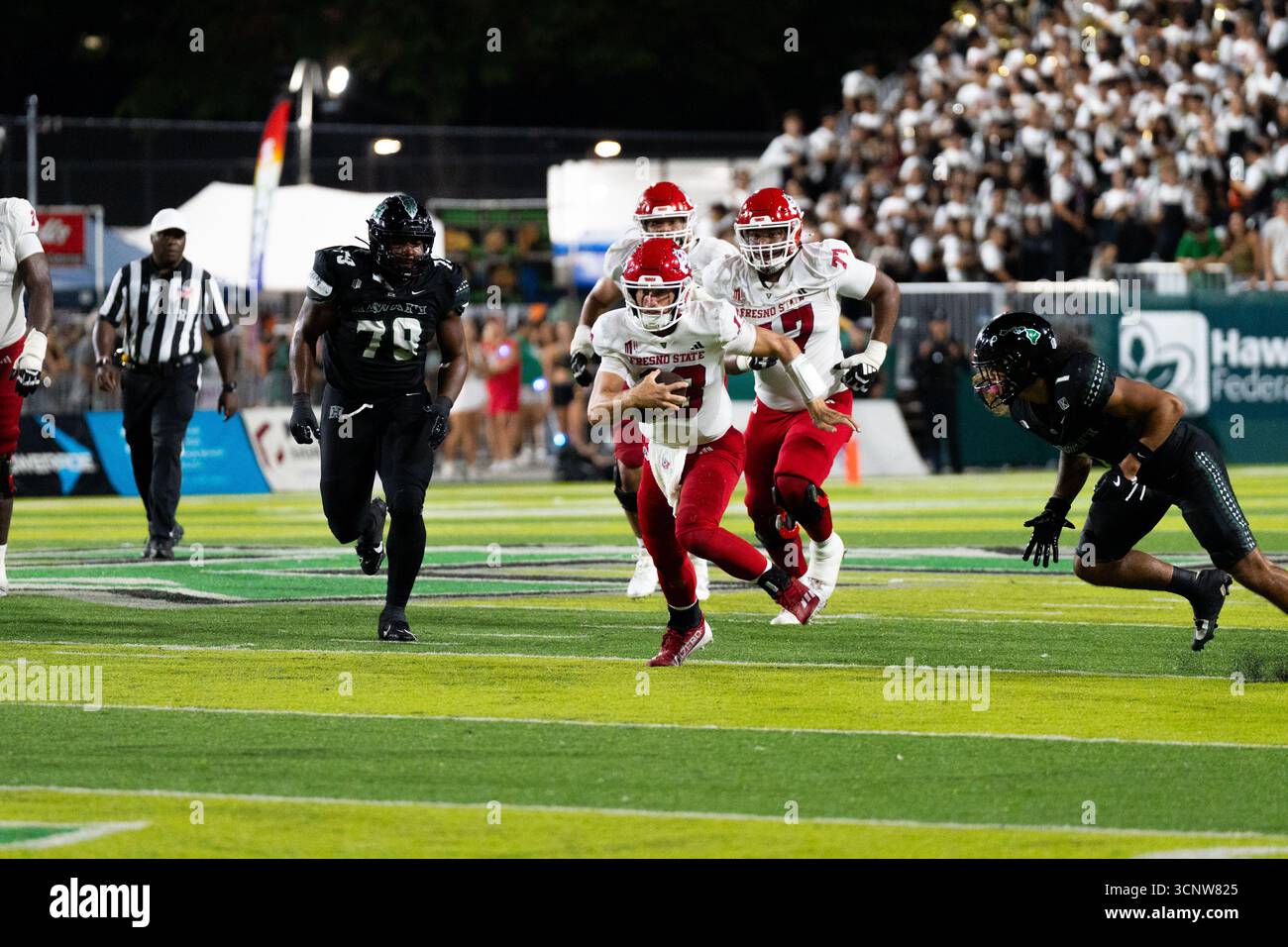 Fresno State QB E.J. Warner se bat contre les défenseurs d'Hawaï dans une victoire étroite de 23 à 21, montrant l'agilité sous pression. Banque D'Images