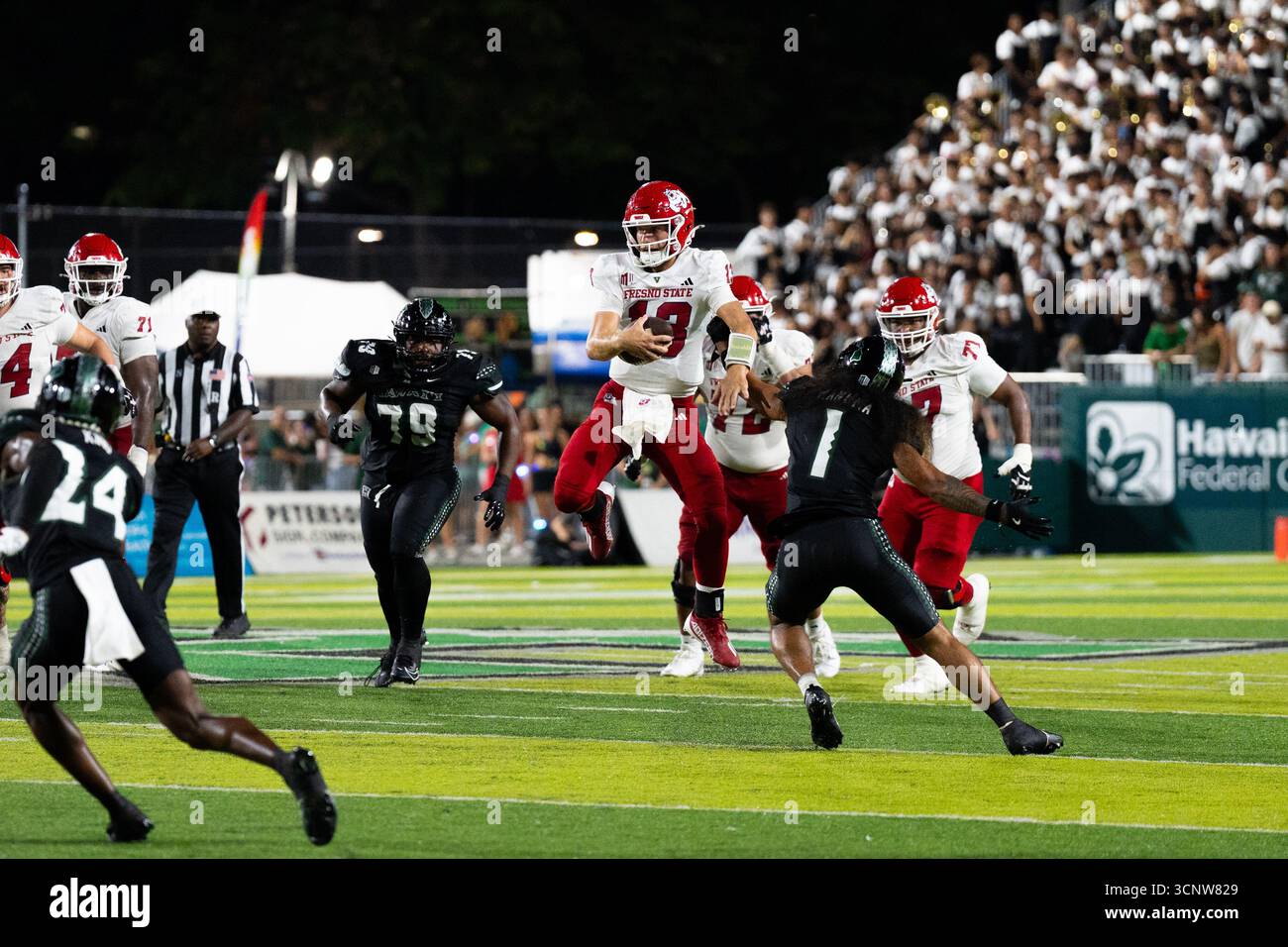 Fresno State QB E.J. Warner se bat contre les défenseurs d'Hawaï dans une victoire étroite de 23 à 21, montrant l'agilité sous pression. Banque D'Images