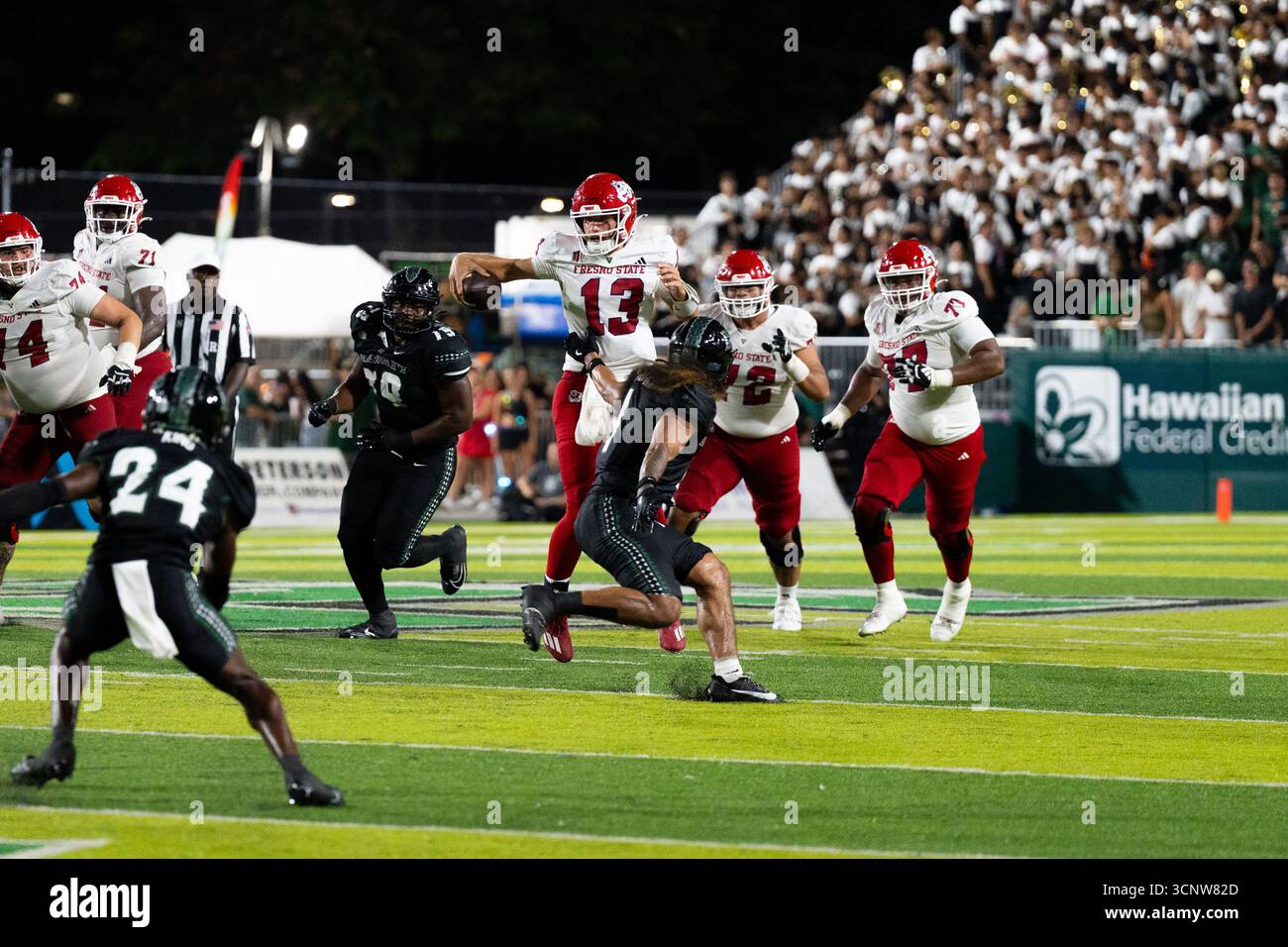 Fresno State QB E.J. Warner se bat contre les défenseurs d'Hawaï dans une victoire étroite de 23 à 21, montrant l'agilité sous pression. Banque D'Images