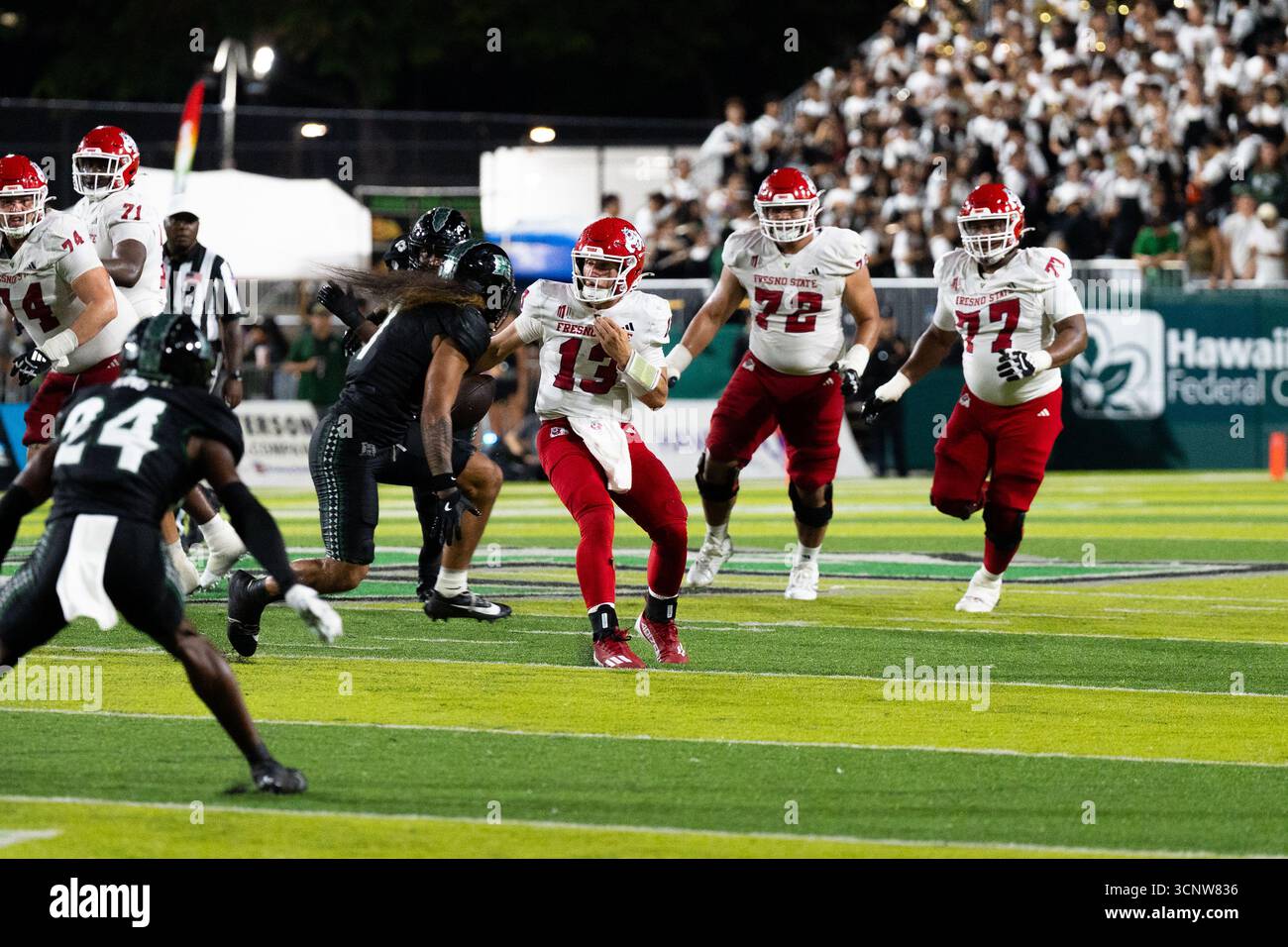 Fresno State QB E.J. Warner se bat contre les défenseurs d'Hawaï dans une victoire étroite de 23 à 21, montrant l'agilité sous pression. Banque D'Images