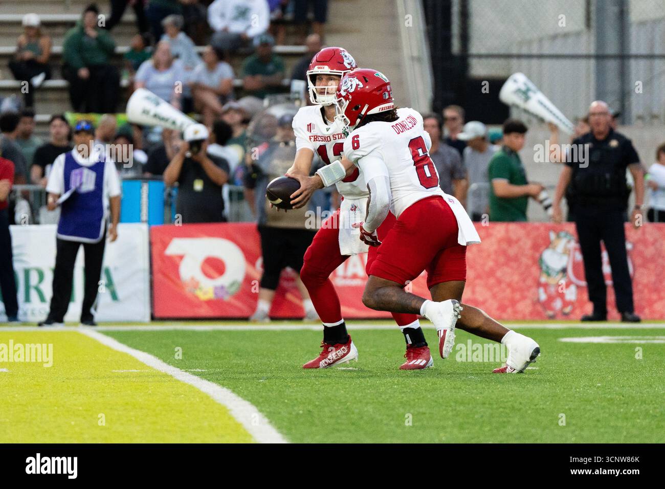 Fresno State QB E.J. Warner passe la main à Bryson Donelson, mettant en place une attaque offensive clé dans ce moment de football à enjeux élevés. Banque D'Images