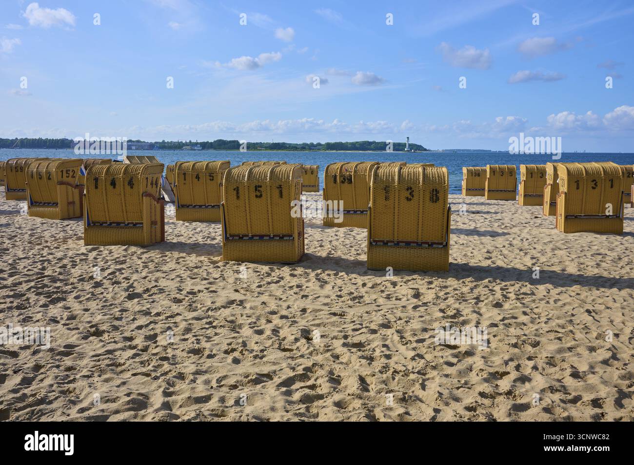 Rangée de chaises de plage numérotées sous un ciel bleu sur une plage de sable ensoleillée, Heikendorf, quartier de Ploen, fjord de Kiel, Schleswig-Holstein, Allemagne Banque D'Images