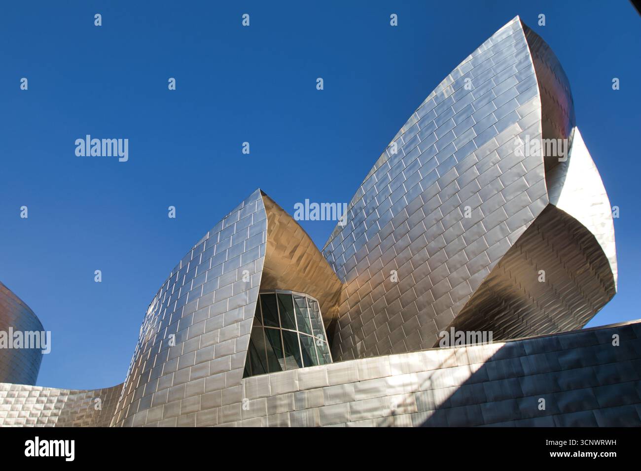 Musée Guggenheim Bilbao sous le ciel bleu. - La magnifique façade du musée Guggenheim, avec ses panneaux en titane uniques reflétant le soleil sous un cl Banque D'Images