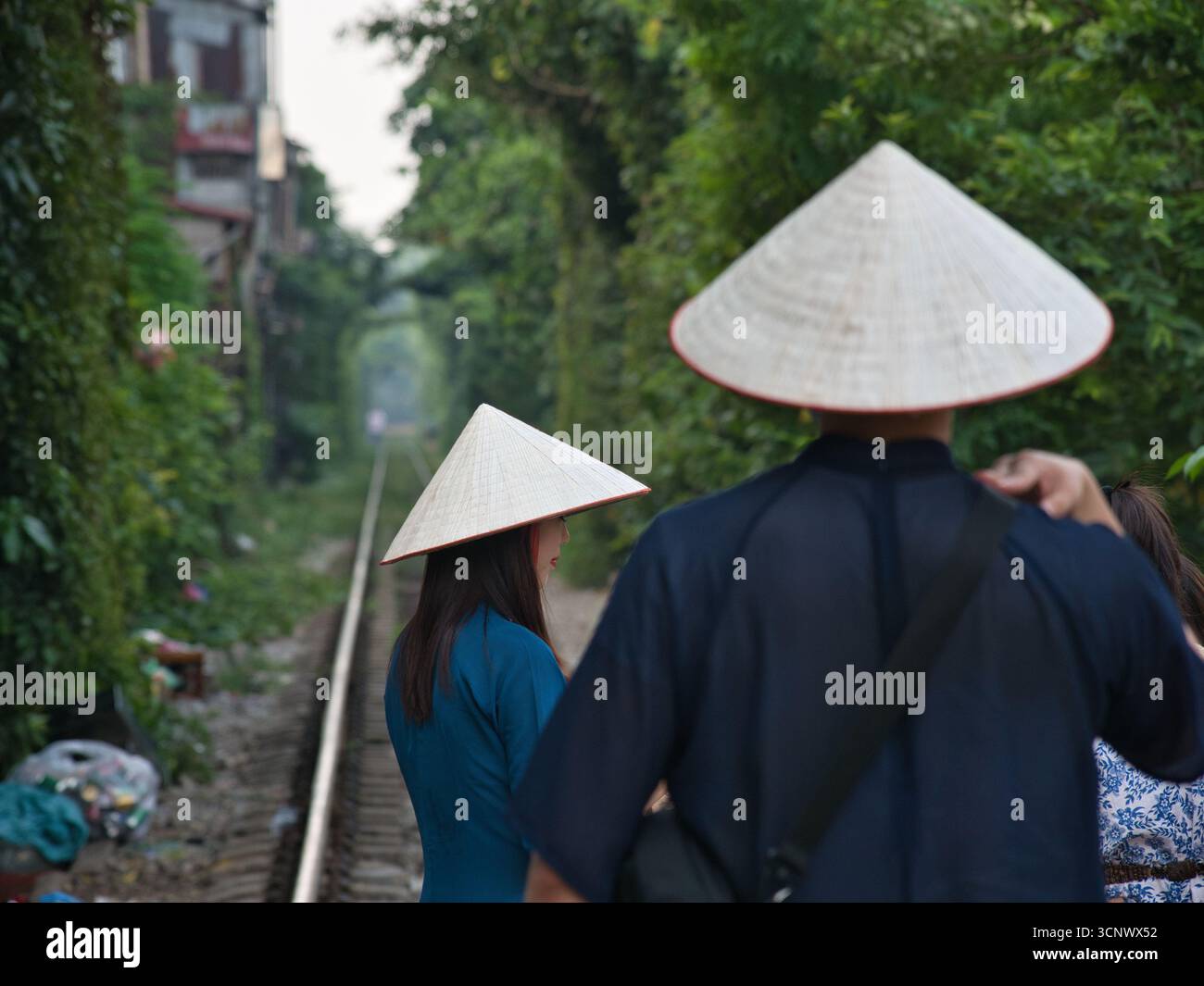 Dos de la personne portant un chapeau conique - Une personne portant un chapeau conique traditionnel, vu de derrière, debout à côté d'une voie ferrée disparaissant dedans Banque D'Images