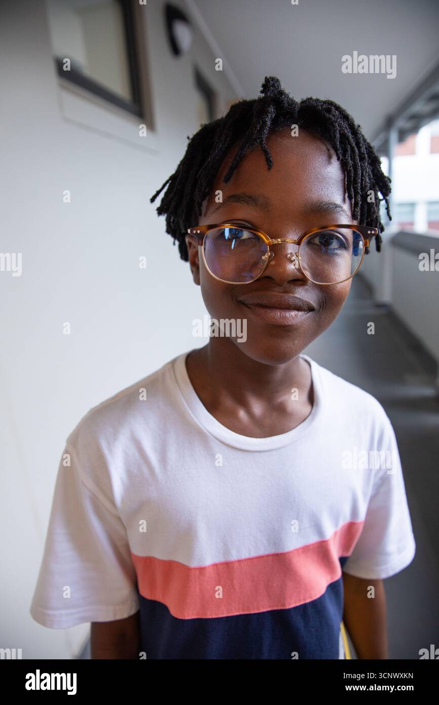Garçon afro-américain d'âge scolaire debout dans une passerelle couverte portant des lunettes Banque D'Images