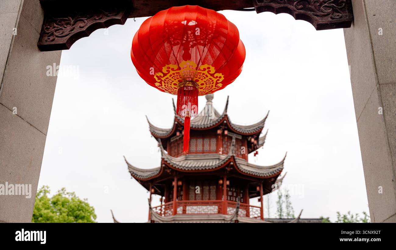 Découvrez la culture vibrante de la ville antique de Qibao, Shanghai, tandis qu'une lanterne rouge ornée est gracieusement suspendue au-dessus d'une pagode chinoise traditionnelle, reflecti Banque D'Images