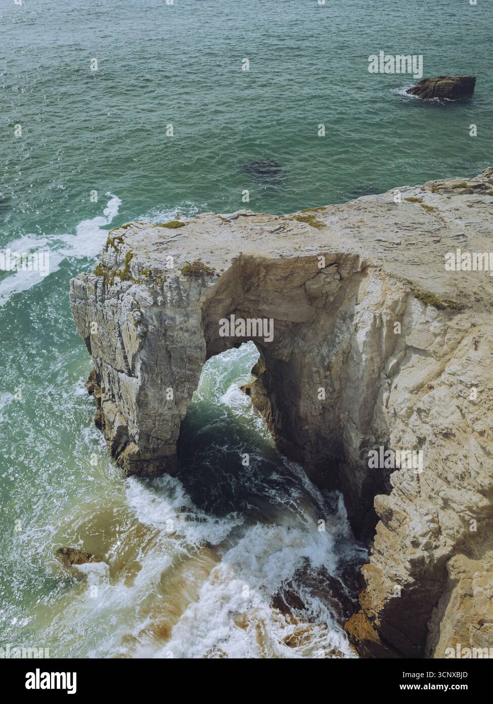 Vue aérienne des falaises escarpées et de couleur crème Arche de Port Blanc Roche percée embrasse l'océan turquoise, les vagues s'écrasant à travers une arche naturelle, une symphonie de la mer rencontre la pierre, Saint-Pierre-Quiberon, Bretagne, France. Banque D'Images