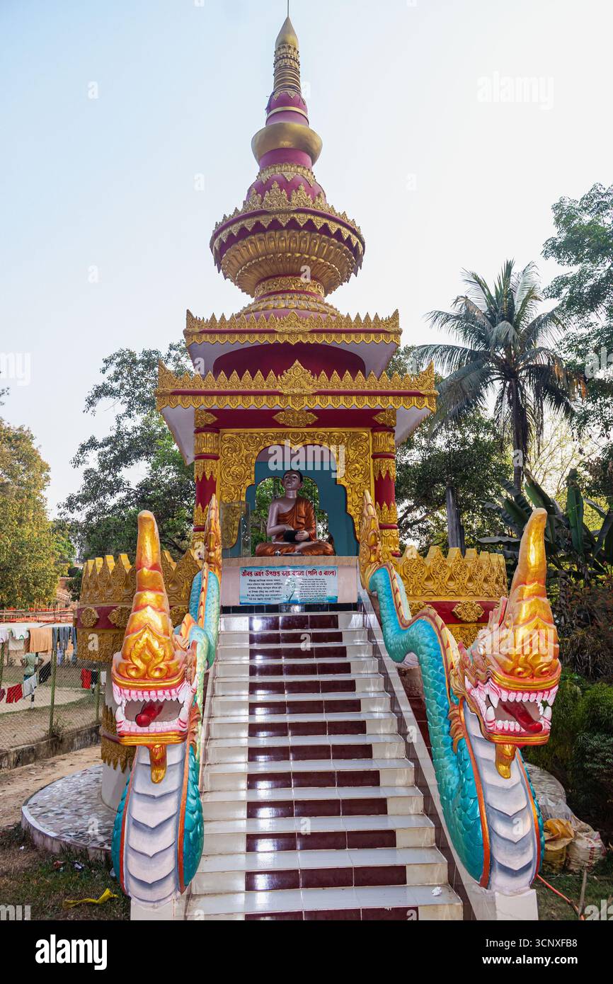 Entrée de pagode bouddhiste ornée de rouge doré avec motifs de dragon et statue centrale de Bouddha. Banque D'Images