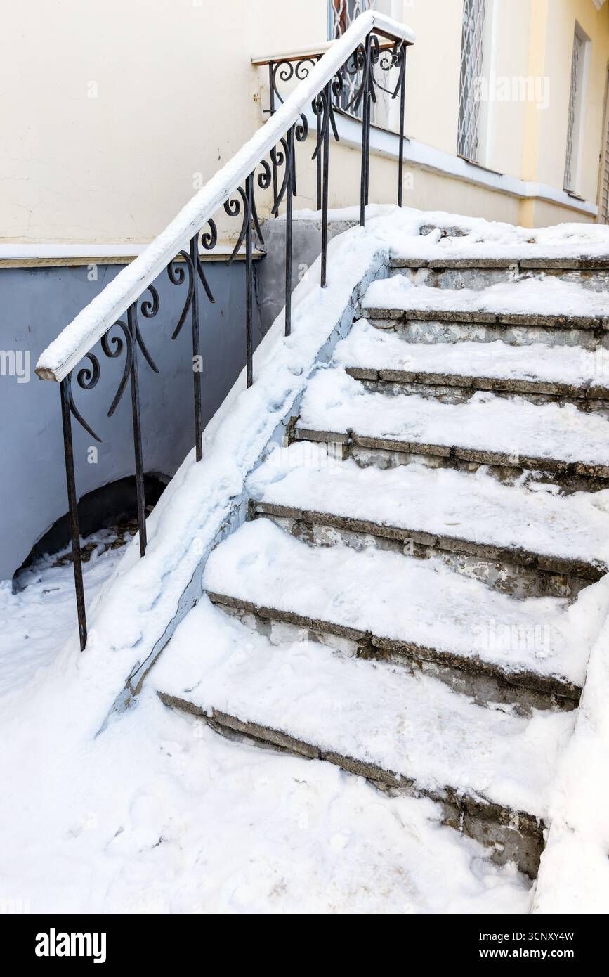 L'escalier en béton recouvert de glace est recouvert de neige fraîche, flanqué d'une balustrade décorative en fer forgé Banque D'Images