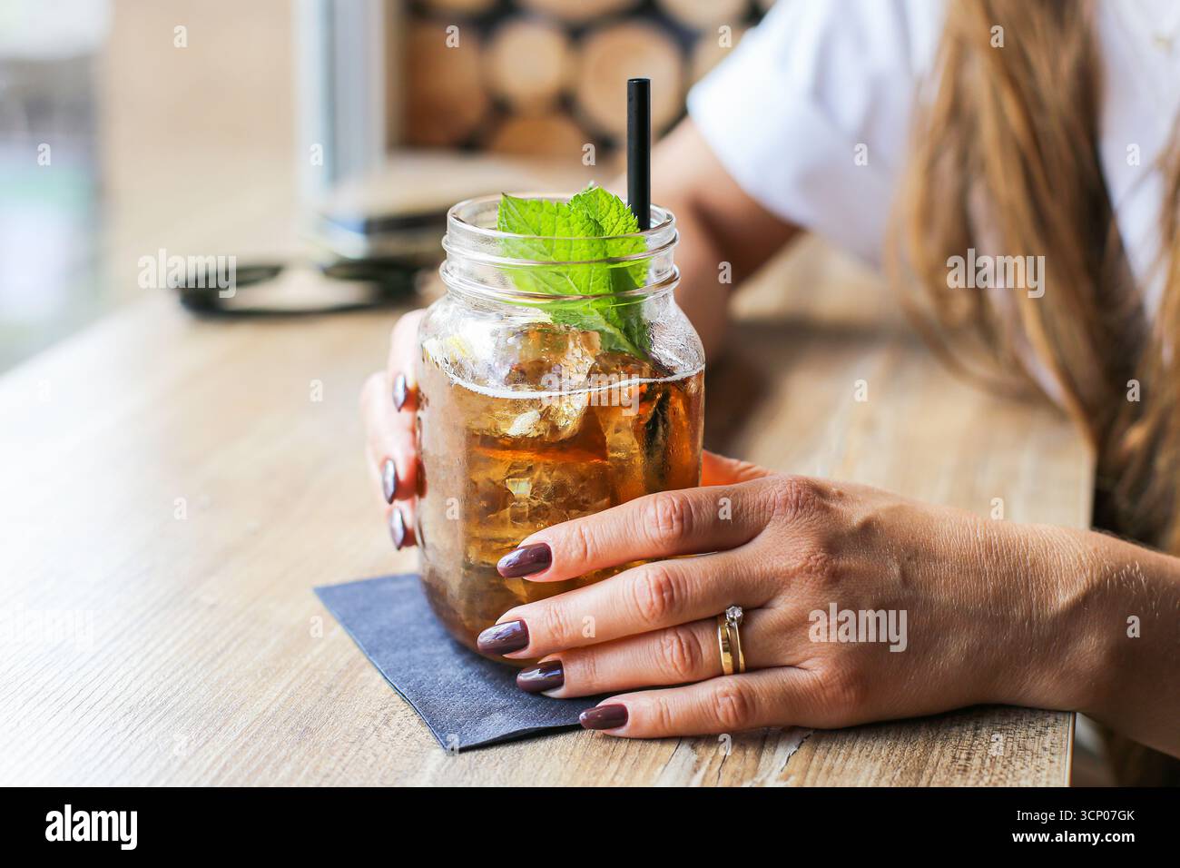 Boisson fraîche rafraîchissante dans un pot mason avec des feuilles de menthe et des glaçons. Femme tenant du verre. Gros plan sur les boissons estivales. Mode de vie sain et détente. Banque D'Images