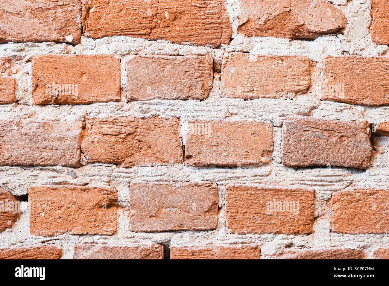 Gros plan sur le mur de briques marron orange. Surface rugueuse avec fissures naturelles et ciment. Fond vintage rustique. Ancienne texture de matériau de construction. Banque D'Images