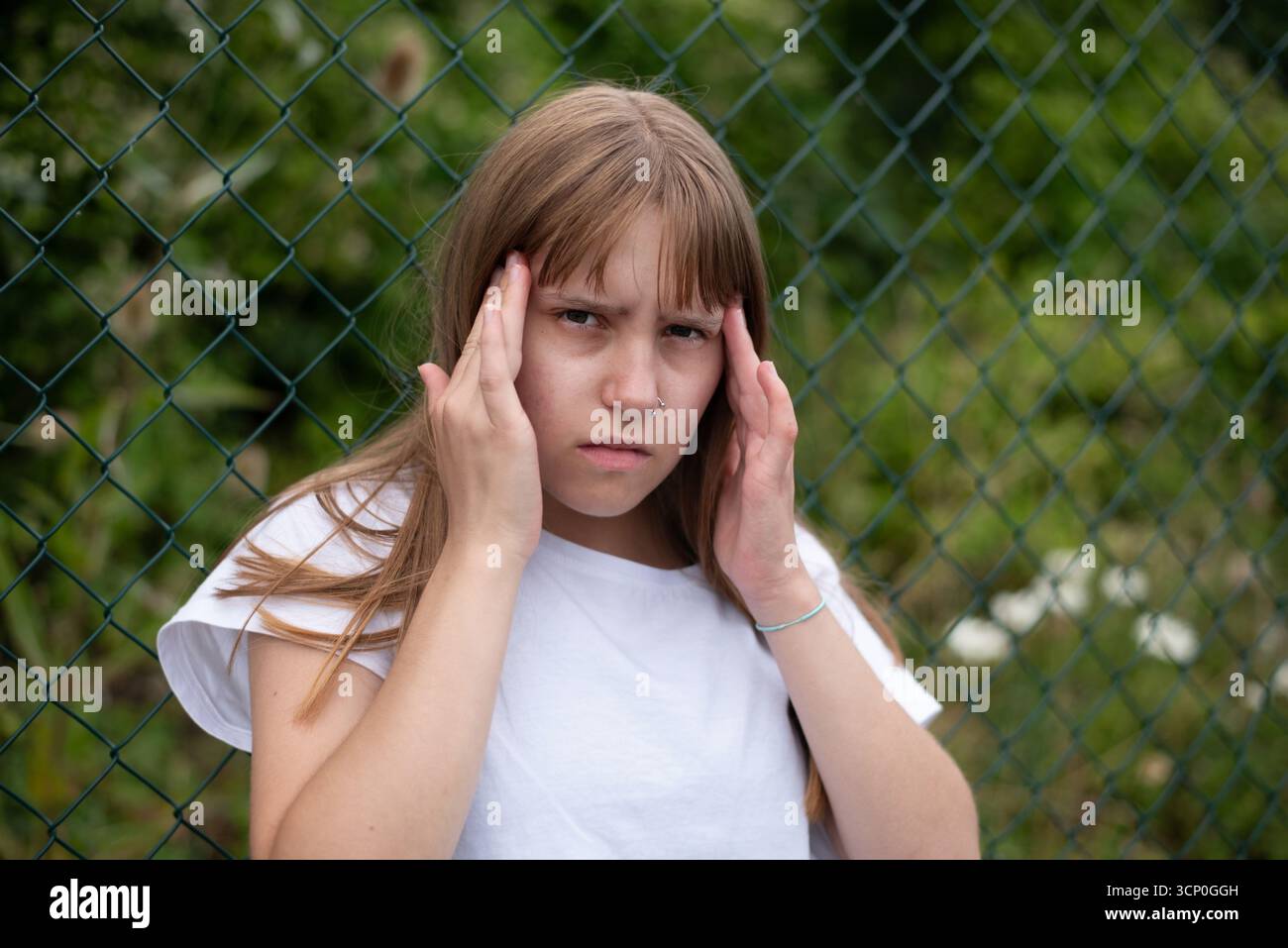 Une fille a eu mal à la tête en marchant dans la forêt, probablement parce qu'elle passe trop de temps à la maison et sort rarement dans la nature. Céphalées Banque D'Images