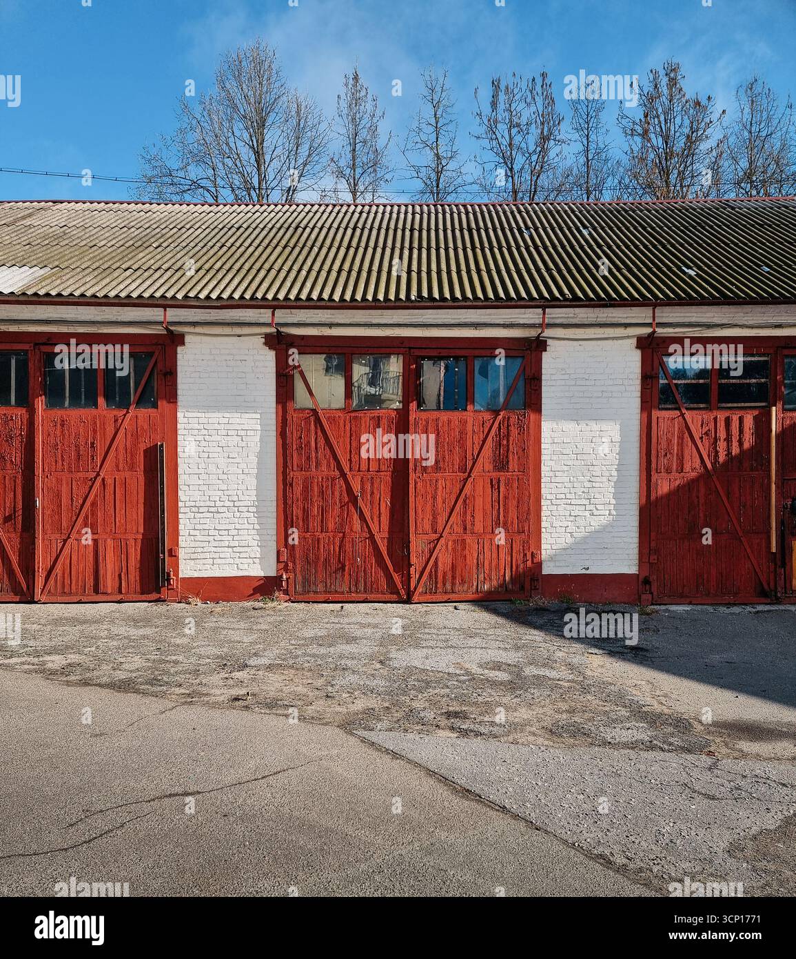 Bâtiment utilitaire avec trois portes de garage - grange ou hangar. Bloc de garages avec portes en bois brun-rouge. Banque D'Images