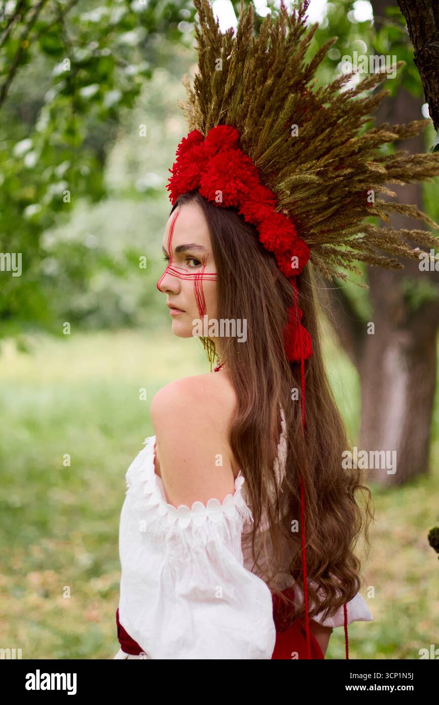 Jeune femme en costume folklorique ukrainien traditionnel avec de longs cheveux, portant une coiffe faite à la main faite d'oreilles de blé et de fleurs rouges Banque D'Images