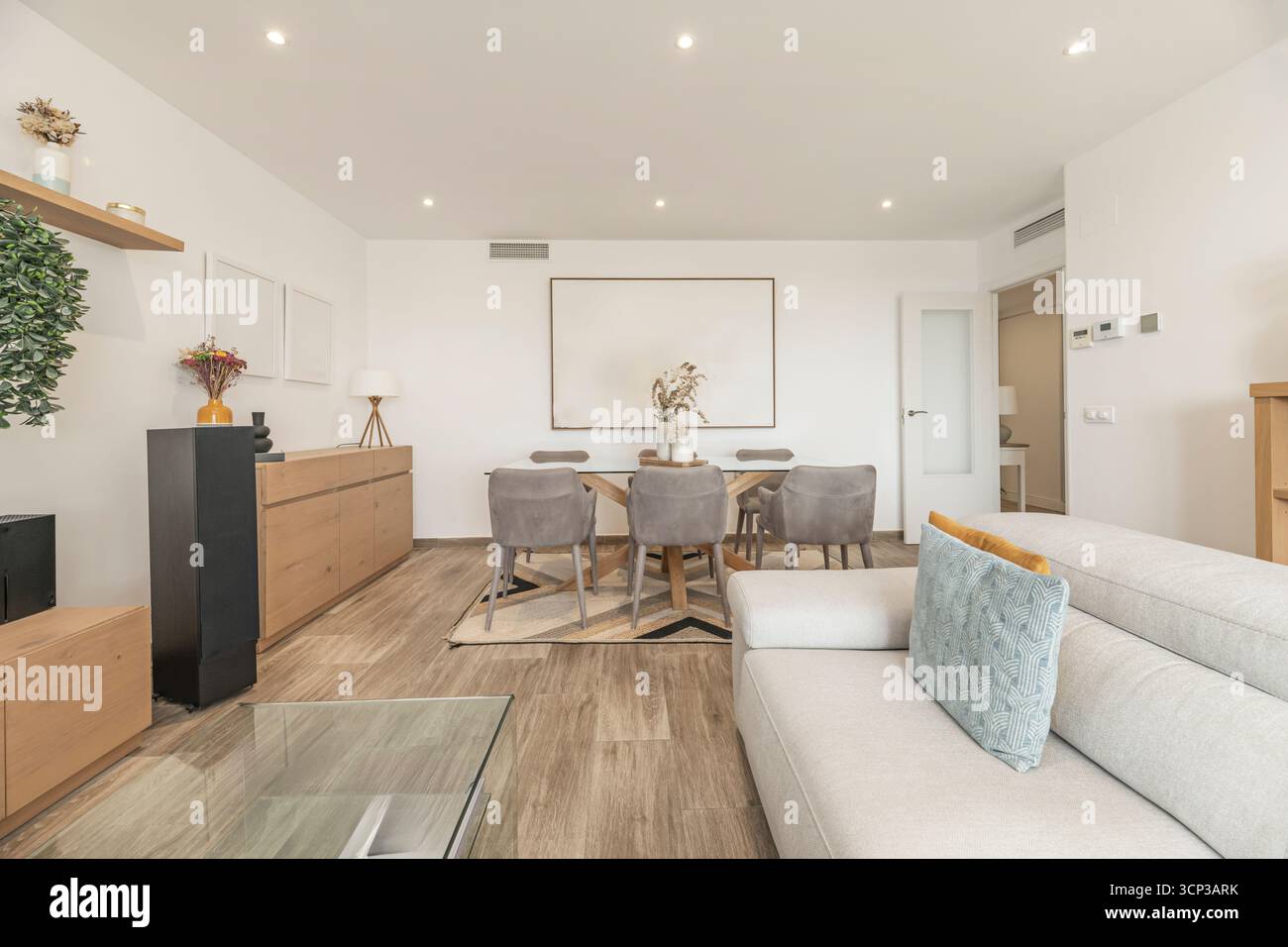 Ambiance chaleureuse avec canapé en lin, table basse en bois massif et salle à manger avec banc et chaises en osier Banque D'Images