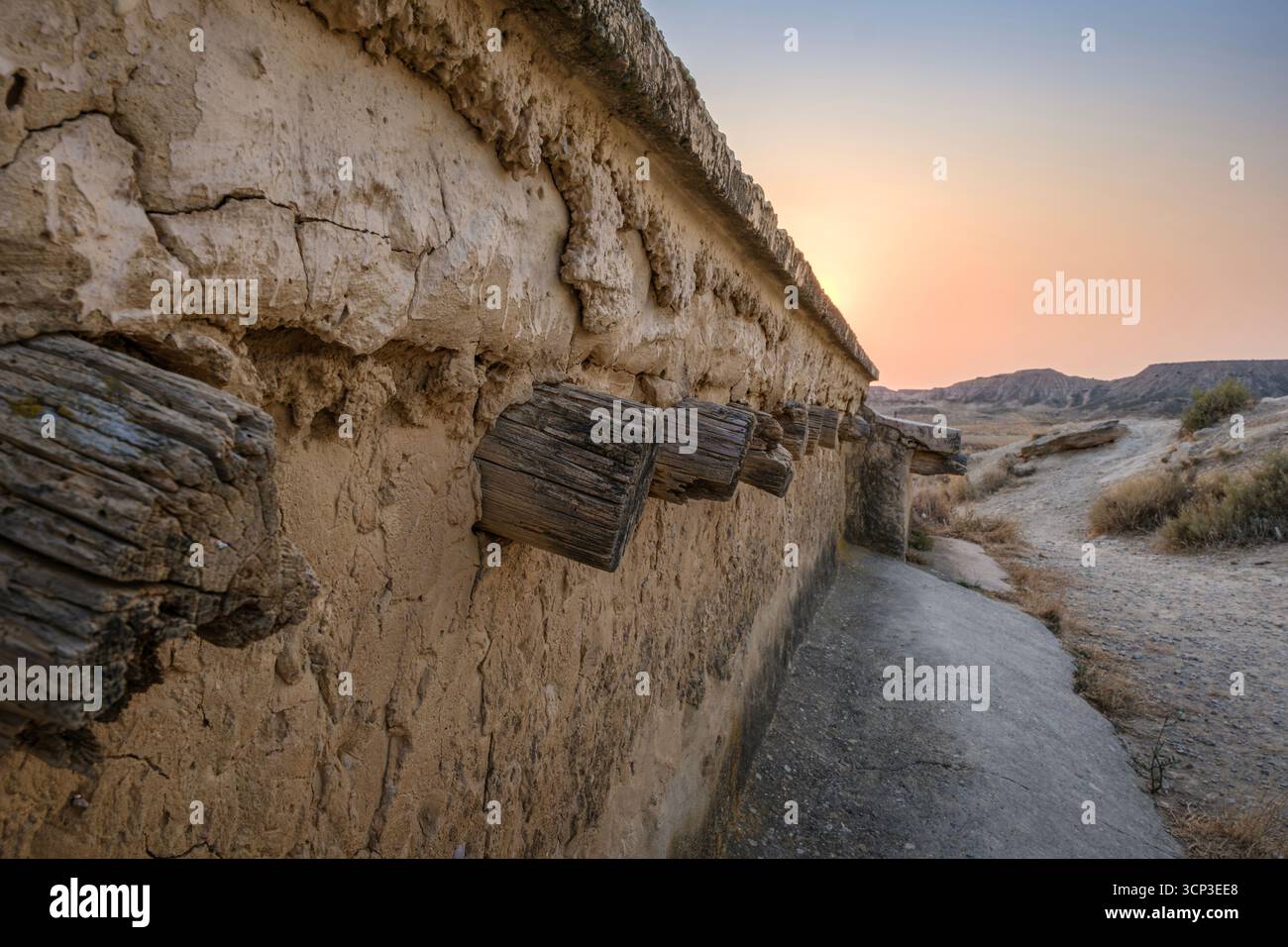 Mur de boue érodé avec poutres en bois dans paysage de désert au coucher du soleil. Bardenas Reales, badlands, Castildetierra, semi désert, Navarre, Espagne Banque D'Images