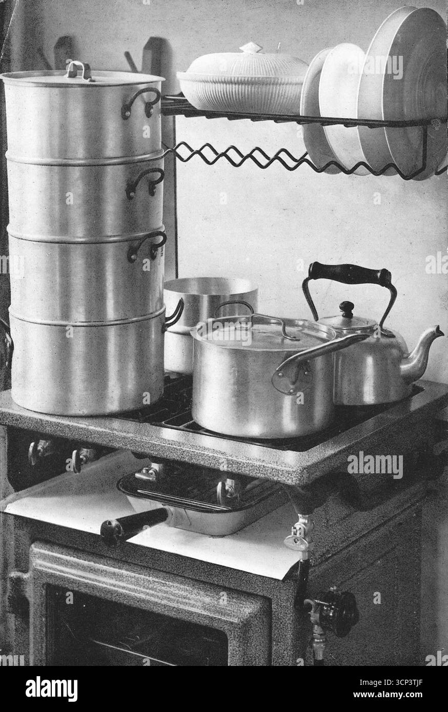Grandes casseroles vapeur à plusieurs niveaux avec casseroles et une bouilloire sur un four Vulcan. D'après une photographie imprimée qui parut à l'origine dans la publication, The Vulcan Cook Book, qui fut publiée en 1936 par la Vulcan Stove Company d'Exeter, en Angleterre. Banque D'Images