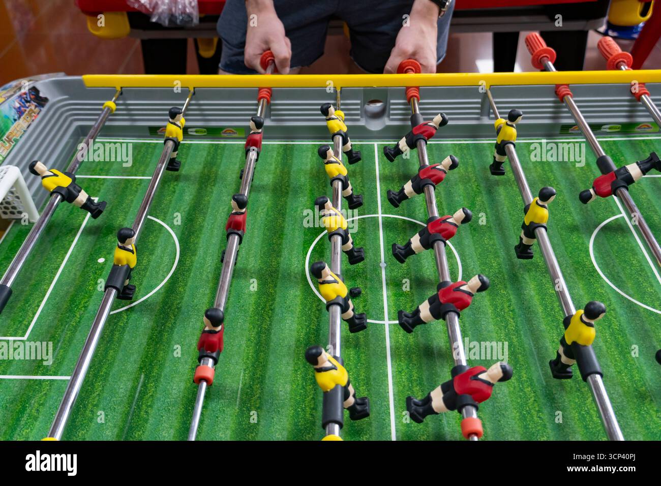 Gros plan d'un match de baby-foot avec des équipes jaunes et rouges en jeu, capturant l'excitation et l'esprit de compétition du football de table Banque D'Images