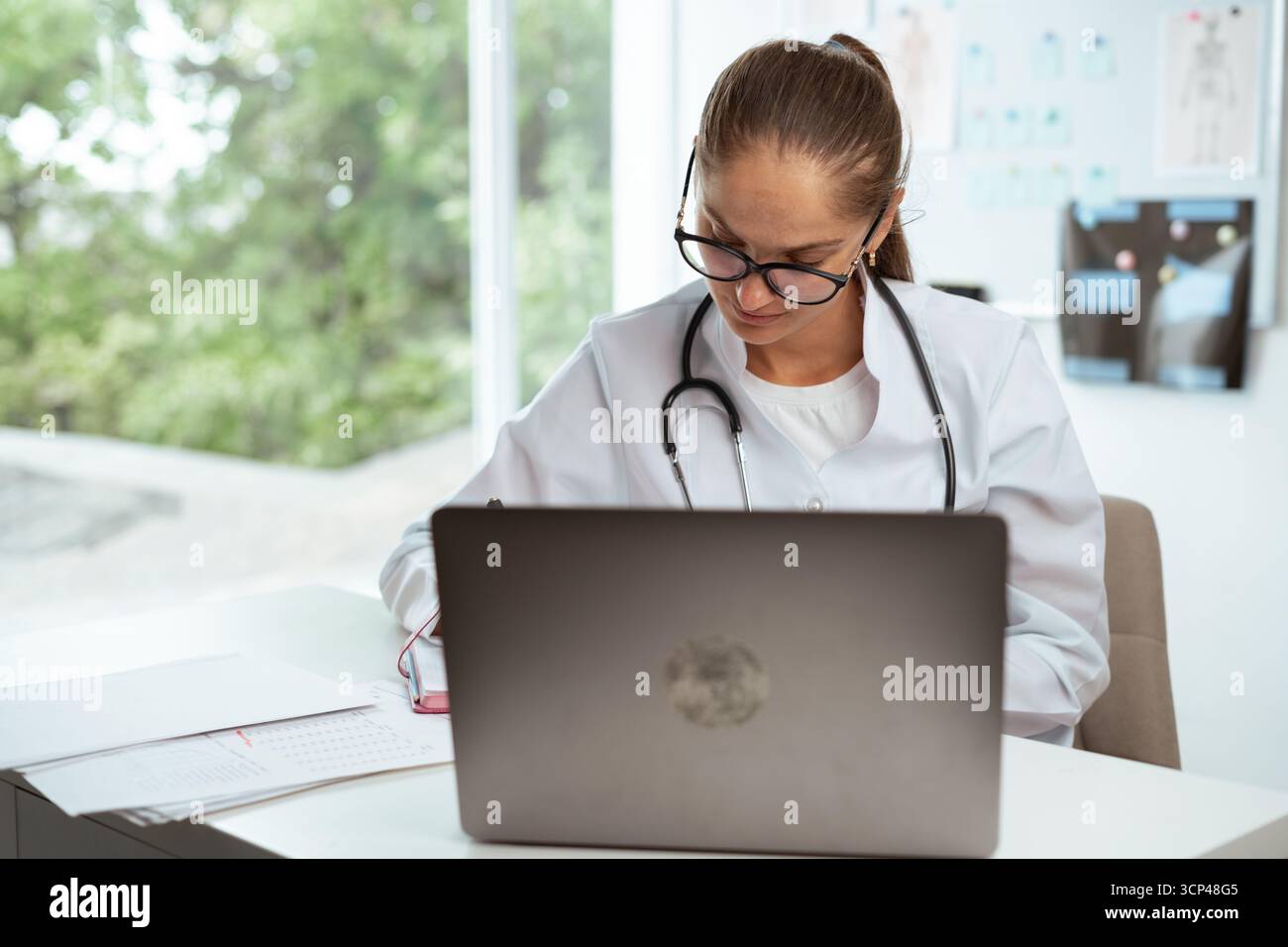Pensant médecin écrivant des notes lecture des dossiers médicaux sur ordinateur portable, analyse des informations du patient. Concept de médecine Banque D'Images