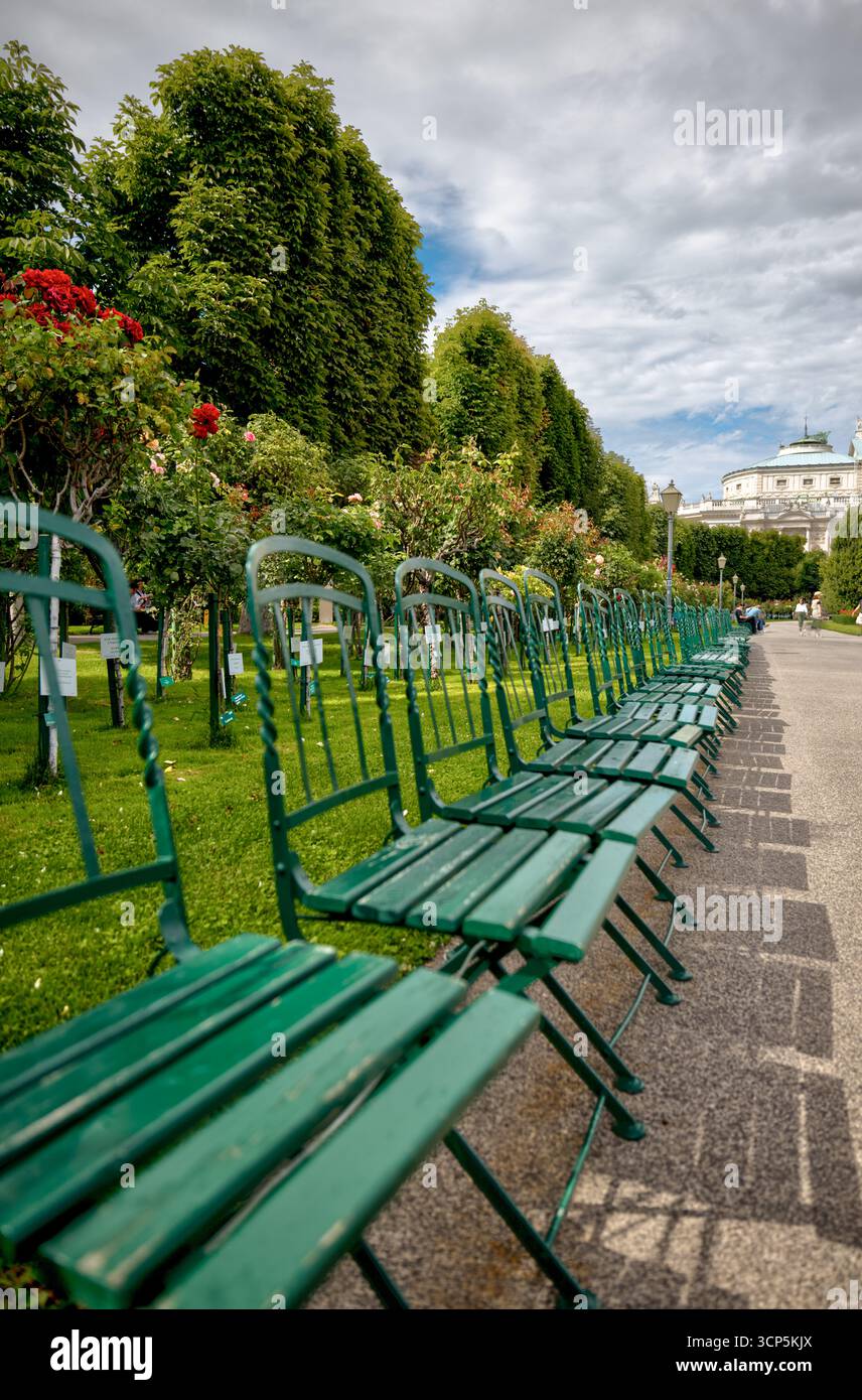 Des rangées vides de chaises vertes bordent les allées ombragées du parc Volksgarten à Vienne, un jardin public populaire connu pour ses collections de roses et ses neo Banque D'Images