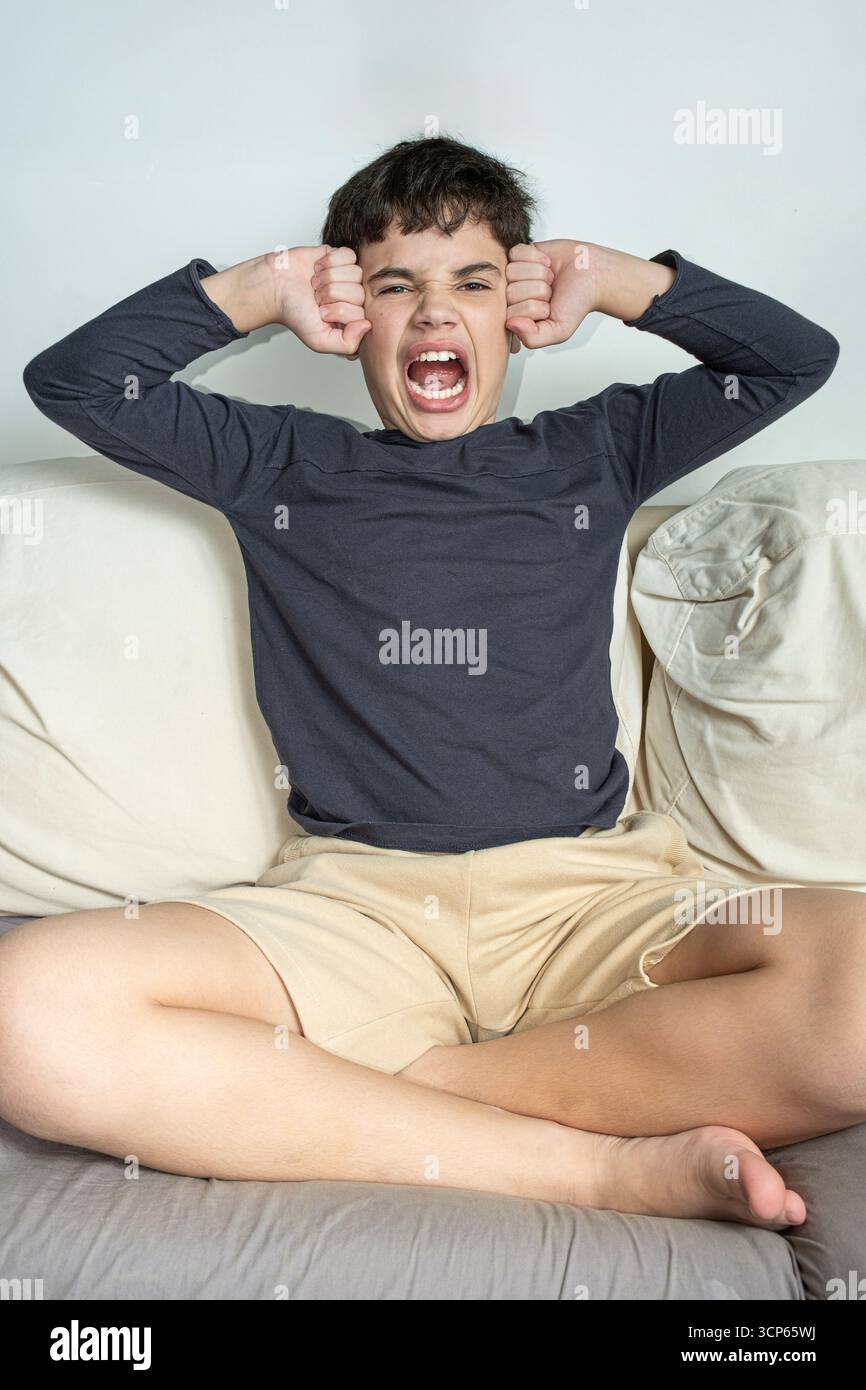 Adolescent brésilien de 12 ans criant et pressant ses poings contre ses temples vertical. Banque D'Images